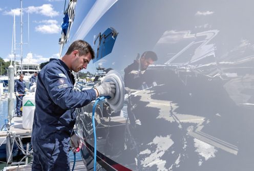 A marine worker is securing and maintaining the boat’s side panel for a clean, polished look.