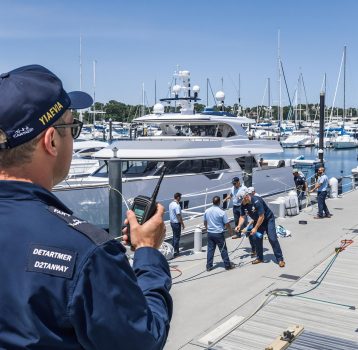 A supervisor overseeing a mooring operation as crew members secure a yacht at the dock.