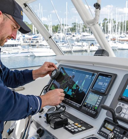 A technician is configuring a marine radar system and navigation display inside a boat.