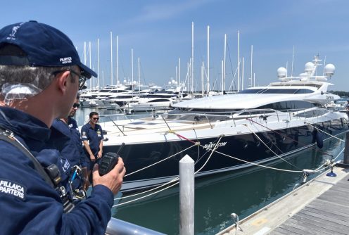 A yacht crew handling ropes and preparing for docking at a marina.