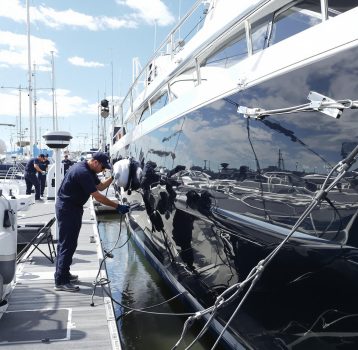 A yacht detailing team is applying the final polish to a luxury vessel at the dock.