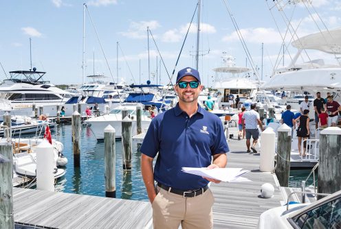 Dock supervisor overseeing charter boat management services with paperwork in hand