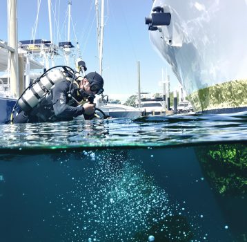 A diver prepares to clean a boat’s hull, removing barnacles and marine growth. Barnacle Removal and Hull Cleaning ensures peak vessel performance.