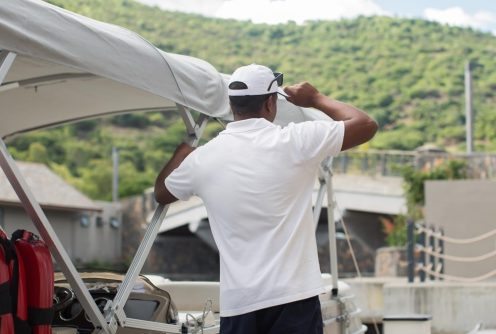A man inspecting a boat’s canopy at a dock, ensuring proper setup.