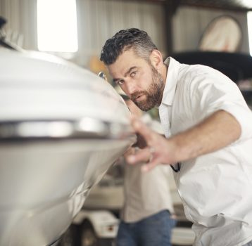 Man checking bodywork on boat in repair workshop