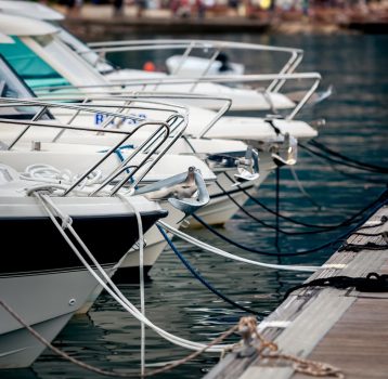 A row of boats securely docked at a marina with proper mooring.