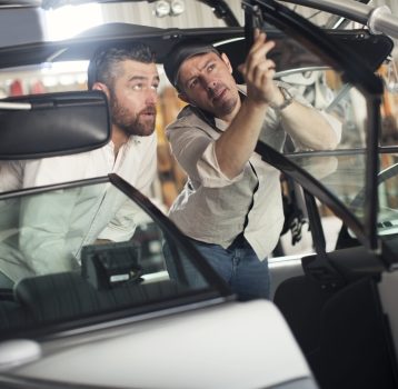 Two men checking motor boat in repair workshop